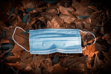 disposable protective mask on the ground of dry leaves, concept of early autumn. Coronavirus 2019. autumn landscape