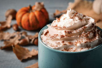Delicious pumpkin latte with whipped cream on table, closeup