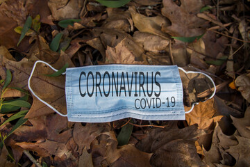 disposable protective mask on the ground of dry leaves, concept of early autumn. Coronavirus 2019. autumn landscape