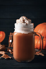 Delicious pumpkin latte on black wooden table, closeup
