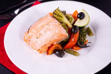Fototapeta na wymiar Baked salmon with vegetables on a white plate, restaurant dish