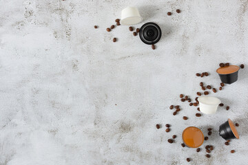 Espresso coffee capsules and roasted coffee beans on grey background top view.