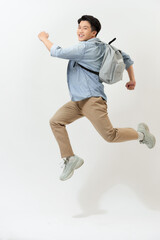 happy smiling young man with backpack jumping in air over white background