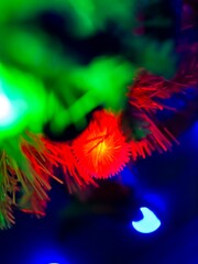 Close-up of colorful garland on white christmas tree hung with blue christmas toys with blurred background.