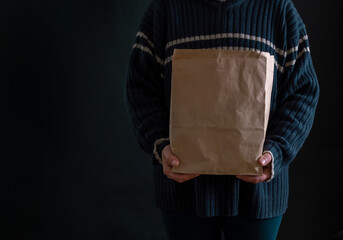 hand holding paper bag beggar black background