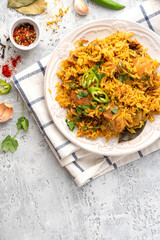 Homemade arabic chicken biryani on a plate top view. Indian food. Spicy chicken with rice on a grey background. Copy space for text
