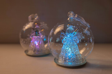 Christmas decoration on the tree, glowing angels in different colors, in a transparent ball