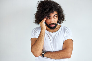 portrait of thoughtful young arabic arabian male isolated in studio, curly dark haired male is thinking about question, pensive expression. doubt concept.