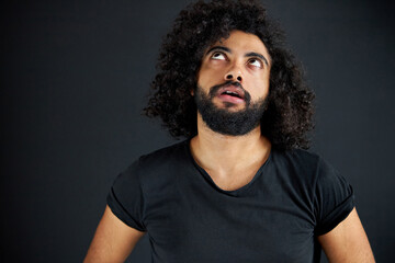 Fototapeta premium what are you talking about. curly male looking up, think. he is tired of listening to talks around, isolated black background