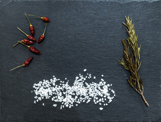 red peppers, rosemary and salt on a black background