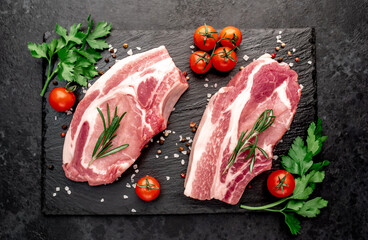 raw pork steaks with spices on a stone background