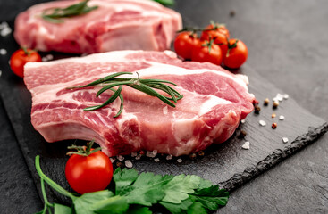 raw pork steaks with spices on a stone background