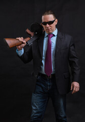 Mature gangster in sunglasses dressed in suit with tommy gun