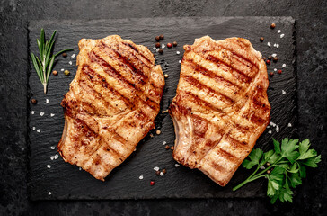 grilled pork steaks with spices on a stone background