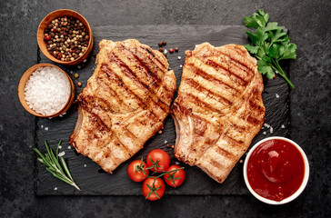 grilled pork steaks with spices on a stone background