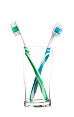 two toothbrushes green and blue stand in a transparent glass isolated on white