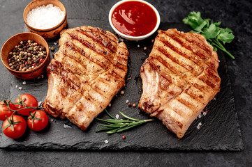 grilled pork steaks with spices on a stone background