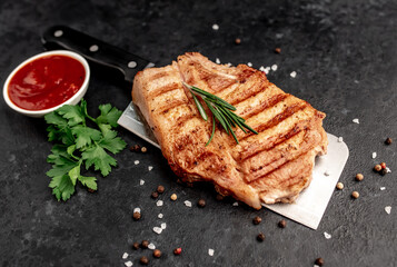 grilled pork steak with spices over a meat knife on a stone background