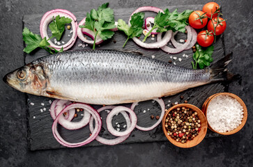 salted fish herring with onions and spices on a stone background 