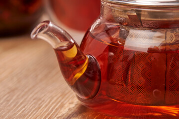 Close-up a hot tea in transparent glass teapot on the table with reflection.