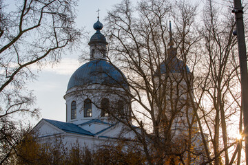 Orthodox church behind flying trees on an autumn evening