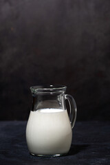 jug with fresh milk on a black background, vertical