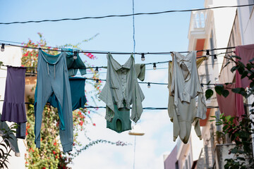 Clothes drying on electric wires on street, blue sky background