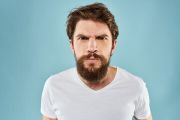 Obraz premium Bearded man in white T-shirt emotions gestures with hands displeased facial expression blue background