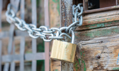 Heavy metal padlock with chain closeup on an entrance gate.