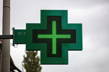 Fototapeta premium Green cross hanging outside drugstore