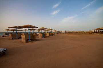 A view of a quiet, deserted sandy beach with umbrellas