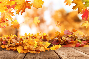 Naklejka na ściany i meble Wooden surface with beautiful autumn leaves on blurred background