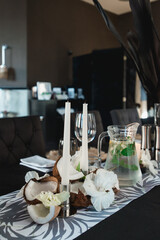 Served tables for wedding banquet with plates restaurant. Decor from fresh flowers, coconuts and leafs