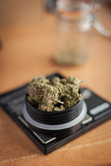 Vertical shot of organic weed buds on a small scale with a glass pot and copy space. 