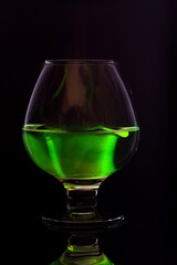 A transparent glass goblet with a green substance. A bright green substance in a glass.