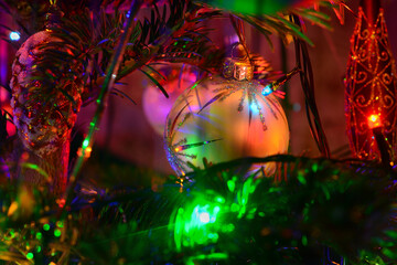 Christmas tree holiday background with glass toys and lights. Colorful decoration close-up in low-key lighting.
