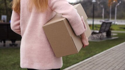Unrecognizable woman carries cardboard box outdoor
