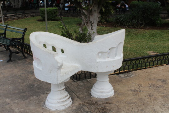 Silla de confindentes color blanca en un parque de una ciudad