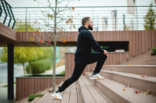 A young man with beard stretching before a run.