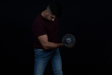 handsome man with dumbbells doing exercises on black background