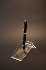 Black fountain pen with golden accessories on a glass stand.
Product photography black and gold fountain pen.
Fountain pen and its black and gold cap