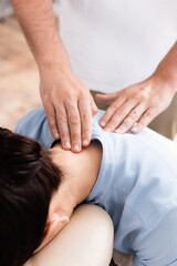 Close up view of masseur doing seated massage of neck for female client