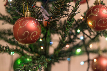 Elegant spruce. The focus is on the ball that hangs on it. There is a garland in the background, no focus on it
