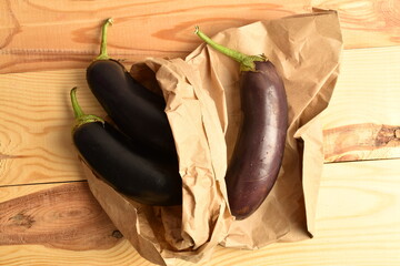 Several ripe dark eggplants, close-up, on a wooden table.