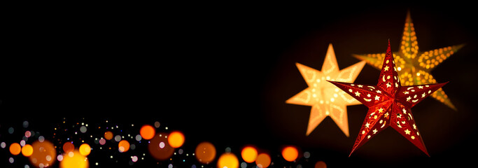 Shining red and gold Christmas star lanterns framing a simple, extra wide black background as copy...