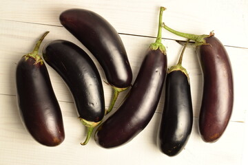 Several ripe dark eggplants, close-up, on a wooden table.