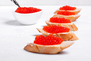 Sandwiches with red caviar and butter on baguette on the white wooden table