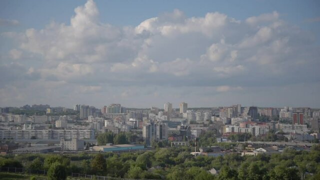 panoramic view of the city, residential buildings, shopping centers, green trees, transport against the backdrop of a blue cloudy sky. can be used for time lapse