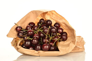 Several ripe cherries berries in a paper bag, close-up, isolated on a white background.