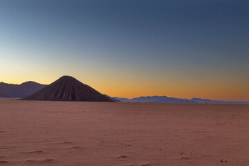 Fototapeta na wymiar Black mountain in foreground and blue mountains in background in the desert